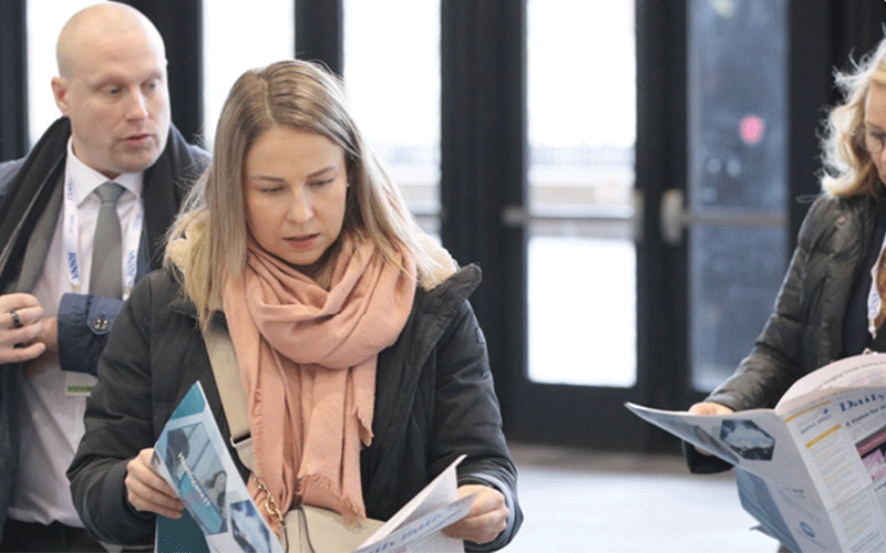 Annual meeting attendees reading Daily Bulletin