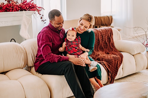 Jesse Conyers MD with spouse and child sitting on a couch. Parents are smiling at the child 