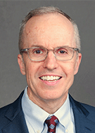 Curtis P. Langlotz, MD, PhD, smiling man wearing glasses and a blue suit, white shirt and red tie