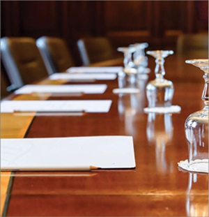 Shutterstock image of an elegant conference table with paper, pens and glassware on it