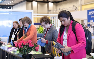 Five women stand along a table assembling kits for community service