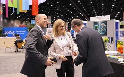 Three people talking and laughing together inside the RSNA 2024 Learning Center