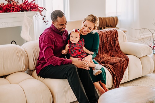 Jesse Conyers MD with spouse and child sitting on a couch. Parents are smiling at the child
