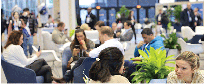 Professionals seated in small groups, looking at phones and computers and engaging in conversations, at the Connections Center of the RSNA annual meeting