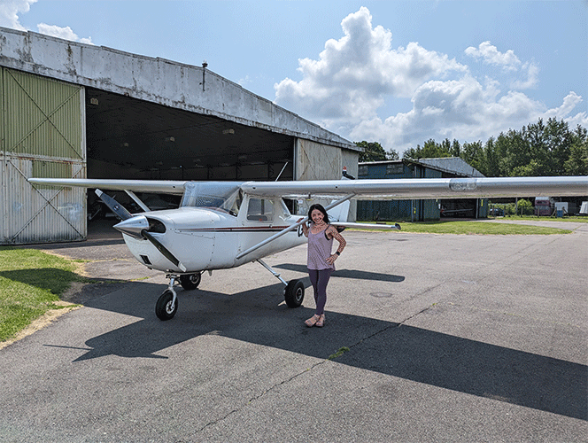Grainne Murphy standing beside small single propeller airplane outside of a hanger at an airfield