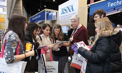 People in professional clothing gathered at a conference reading brochures like the meeting guide