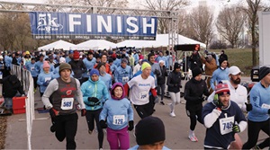 Many runners crossing the finish line of R&E 5k fun run.