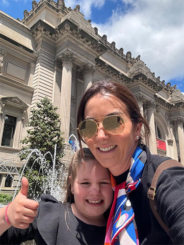 RSNA Member Spotlight Luciana Pardini Chamié, MD, PhD, taking a picture with a child in front of an ornate building.