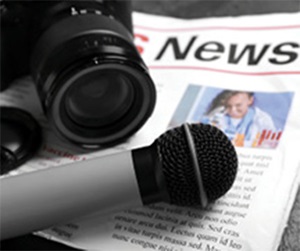 Close up of a video camera and microphone resting on top of a newspaper