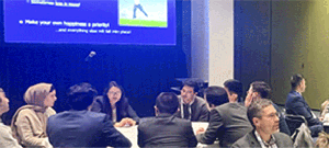 Group of people sitting at table in front of a presentation