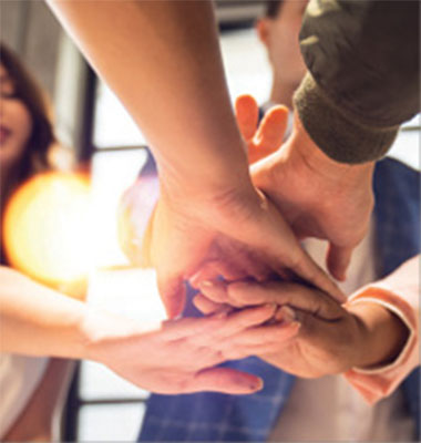Close up view from the underside of the stacked hands of several people in a display of teamwork