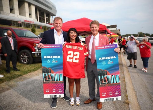 Amy K. Patel, MD, hods a Kansas City Chiefs jersey as she stands between two men who presented her with the award for her 2022 Kansas City Chiefs Fan of the Year recogntion.
