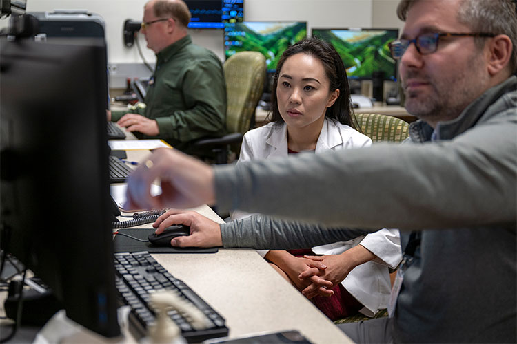 Jennifer Keiko Matsui, MD, PhD, and a fellow physician look at a computer screen. 
