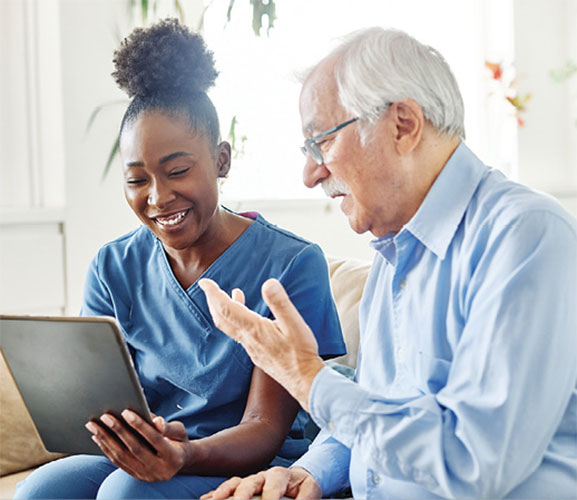 A physician and a patient reviewing health information on a tablet. 