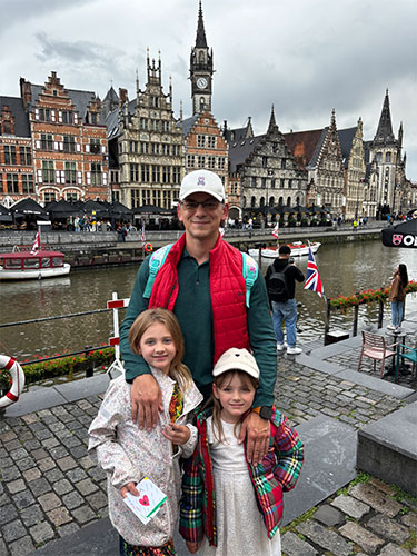 Sergey Morozov, MD, PhD, MPH, stands with two children in front of a canal in a city in Europe.