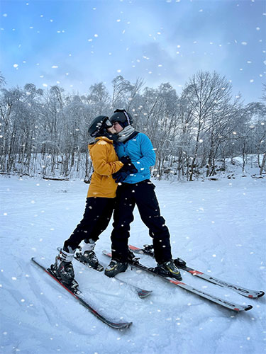 Maria Lucia Brun-Vergara, MD, and partner kiss while standing on snow skis.