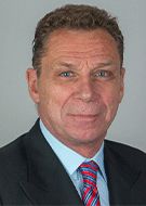 Dieter Enzmann MD wearing dark suit and red tie