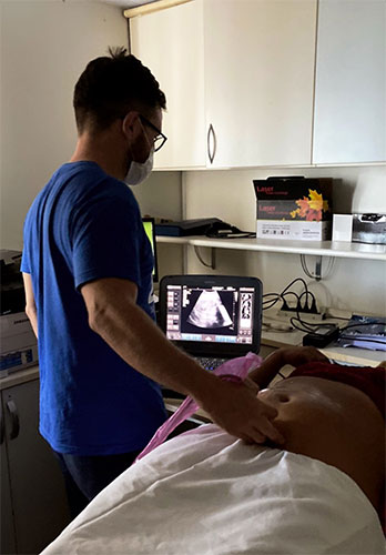 Jose Araujo-Filho, MD, PhD, stands bedside, working with a patient on a medical boat.