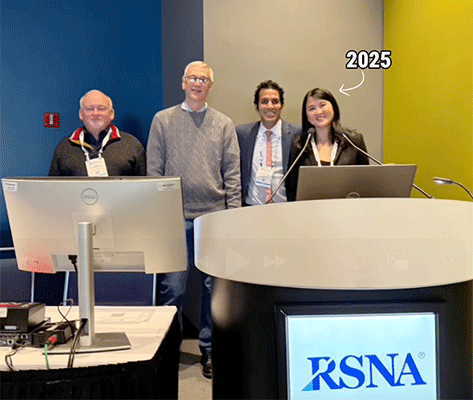 Zi Jill Zhang, MD, MSc, poses behind a podium at RSNA 2025 with a group of three men